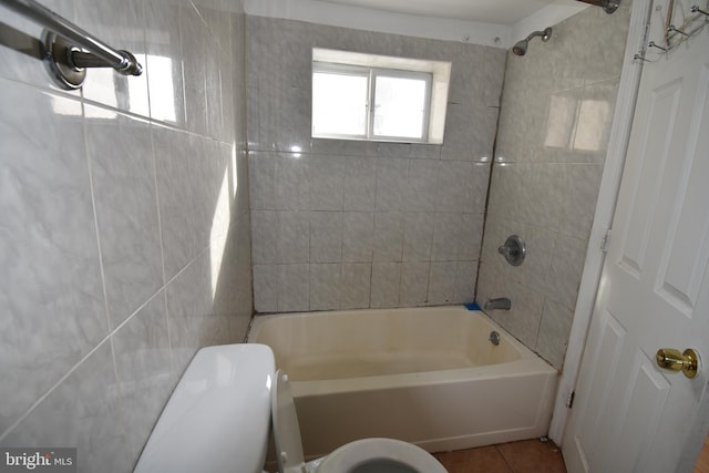 bathroom featuring tile patterned flooring, tiled shower / bath combo, and toilet