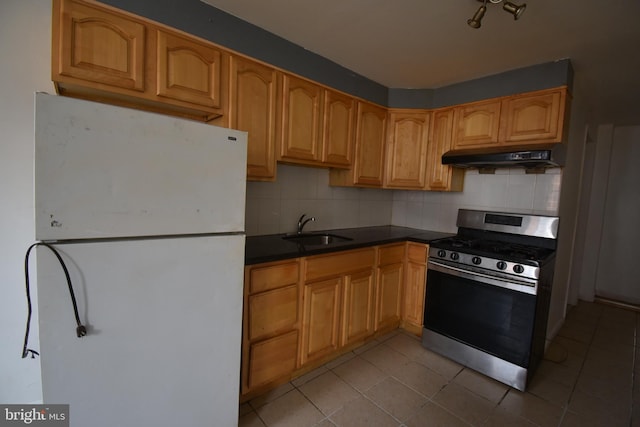 kitchen featuring sink, gas range, tasteful backsplash, light tile patterned floors, and white refrigerator