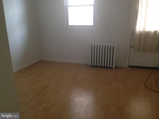 empty room featuring radiator heating unit and light wood-type flooring