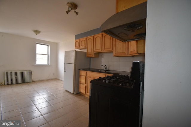 kitchen featuring sink, extractor fan, black range with gas stovetop, radiator heating unit, and white fridge