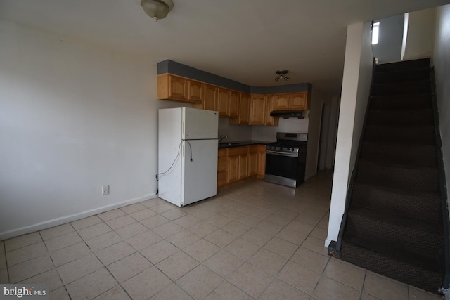 kitchen with sink, light tile patterned floors, gas stove, and white fridge