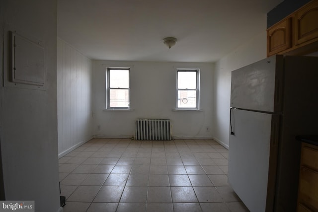 interior space with radiator, light tile patterned flooring, electric panel, and white fridge