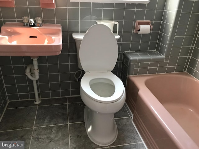 bathroom with tile patterned floors, tile walls, and a washtub