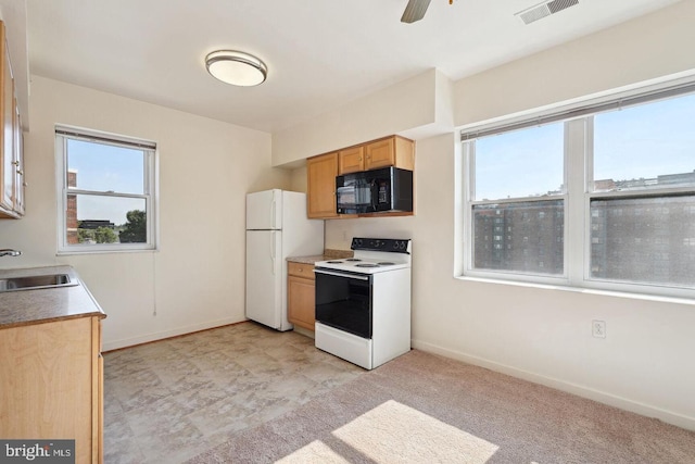 kitchen featuring white appliances, baseboards, visible vents, and a sink