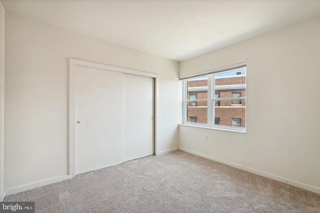 unfurnished bedroom featuring carpet, baseboards, and a closet