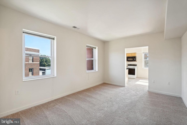 empty room featuring baseboards, visible vents, and light colored carpet