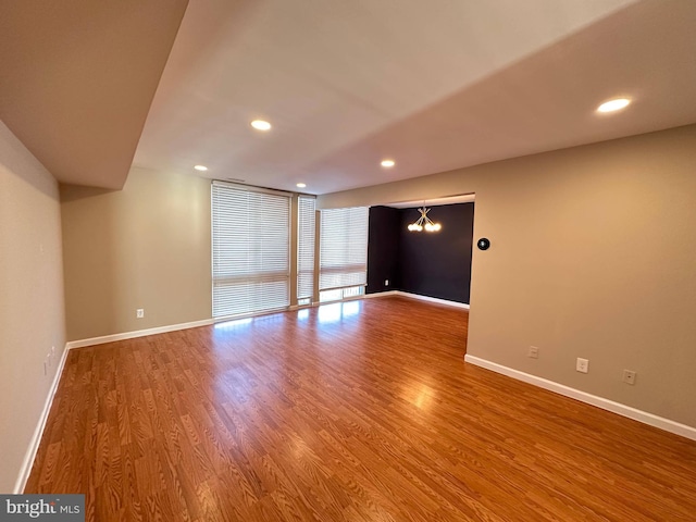 spare room featuring hardwood / wood-style floors, a notable chandelier, and a wall of windows