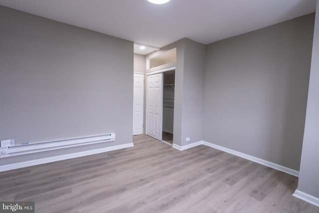 empty room featuring a baseboard radiator and light hardwood / wood-style flooring