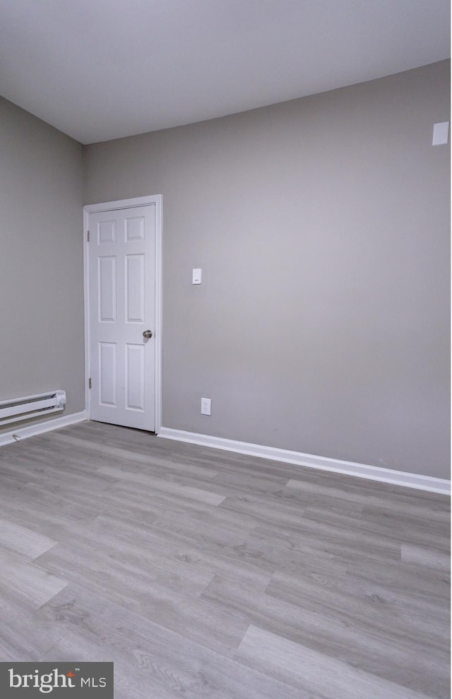 unfurnished room featuring a baseboard heating unit and light wood-type flooring