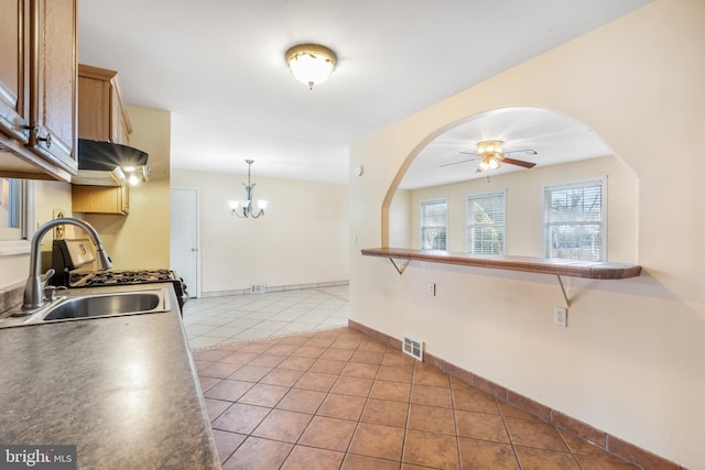 kitchen with sink, light tile patterned floors, ceiling fan with notable chandelier, and hanging light fixtures