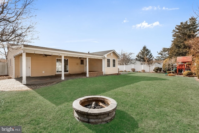 back of house featuring a playground, a patio, a lawn, and an outdoor fire pit