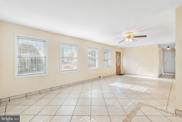 empty room featuring a healthy amount of sunlight, light tile patterned floors, and ceiling fan