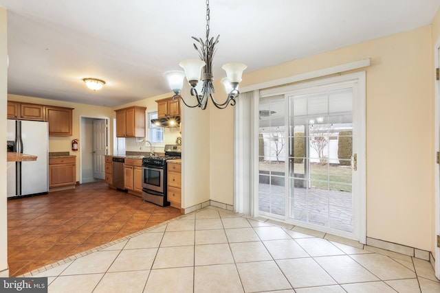 kitchen with pendant lighting, sink, light tile patterned floors, stainless steel appliances, and an inviting chandelier