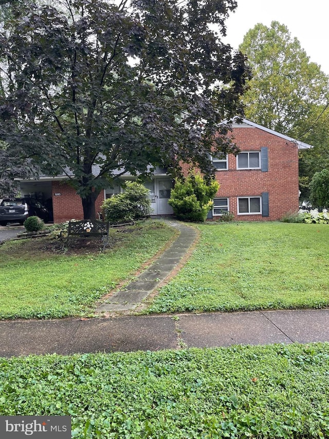 view of front facade with brick siding and a front yard