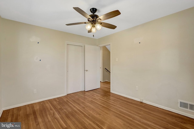 empty room with baseboards, visible vents, ceiling fan, and wood finished floors