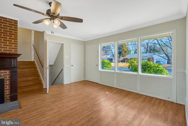 unfurnished living room with ornamental molding, stairway, light wood-type flooring, and a fireplace