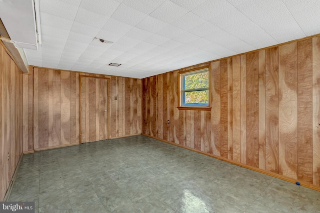 unfurnished room featuring wood walls and tile patterned floors