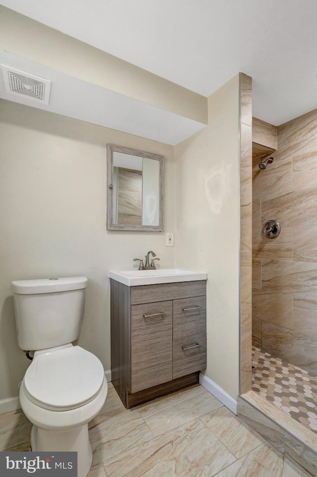 bathroom with toilet, tiled shower, vanity, and visible vents