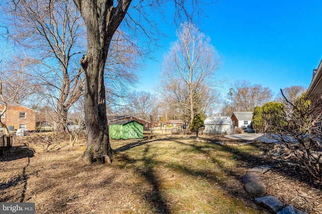 view of yard with an outdoor structure, a shed, and fence