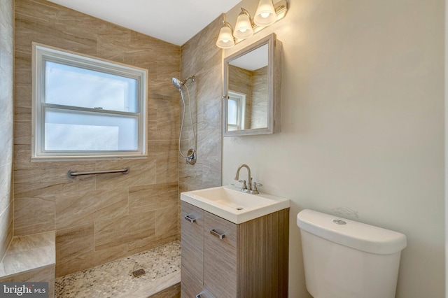 bathroom with tiled shower, vanity, and toilet