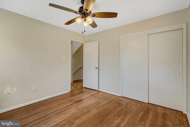 unfurnished bedroom featuring a ceiling fan, a closet, baseboards, and wood finished floors