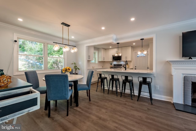 dining room featuring crown molding, a brick fireplace, and dark wood-type flooring