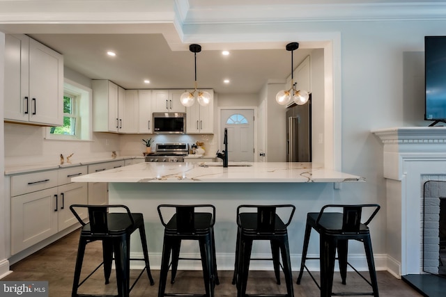 kitchen featuring white cabinetry, appliances with stainless steel finishes, decorative light fixtures, and sink