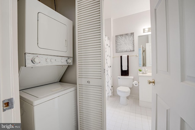 laundry room featuring light tile patterned flooring and stacked washer / dryer