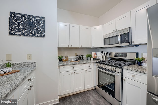 kitchen with dark wood-type flooring, light stone countertops, white cabinets, and appliances with stainless steel finishes