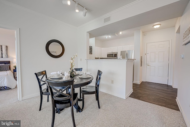 dining room with ornamental molding, rail lighting, and carpet floors