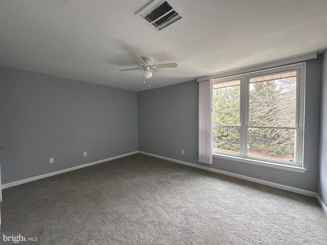 empty room featuring ceiling fan and dark carpet