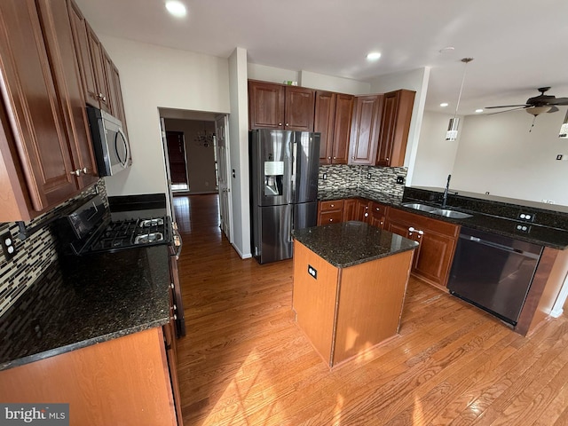 kitchen with a center island, refrigerator with ice dispenser, sink, dishwasher, and pendant lighting