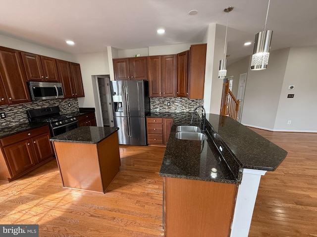 kitchen featuring a kitchen island, sink, stainless steel appliances, and hanging light fixtures