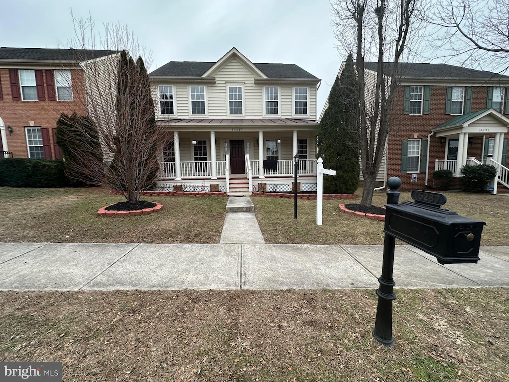 colonial home with covered porch and a front yard