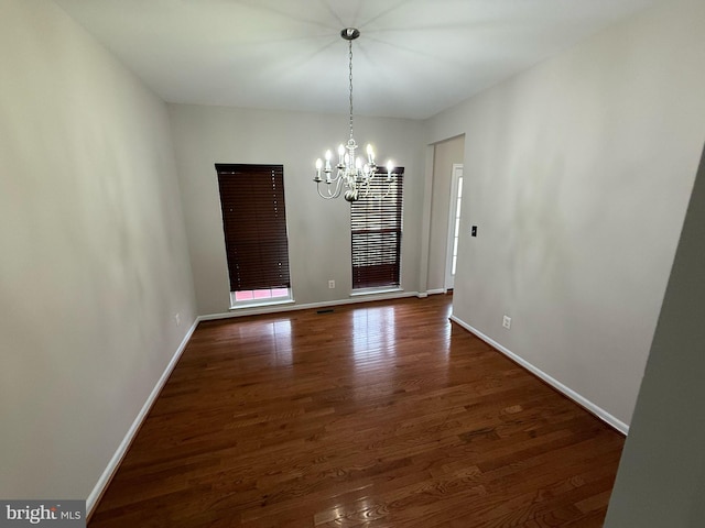 unfurnished dining area featuring a notable chandelier and dark wood-type flooring