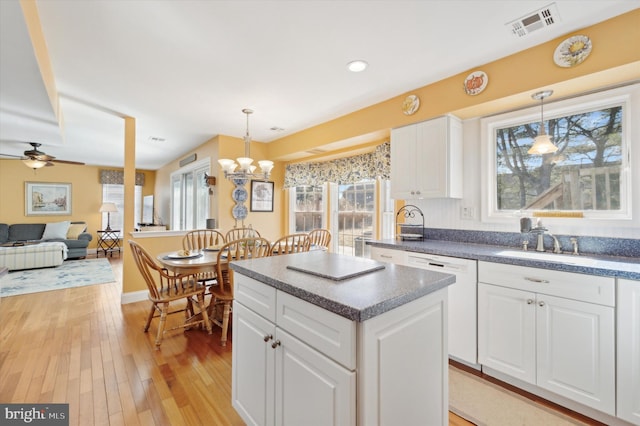 kitchen with pendant lighting, white dishwasher, dark countertops, and white cabinets