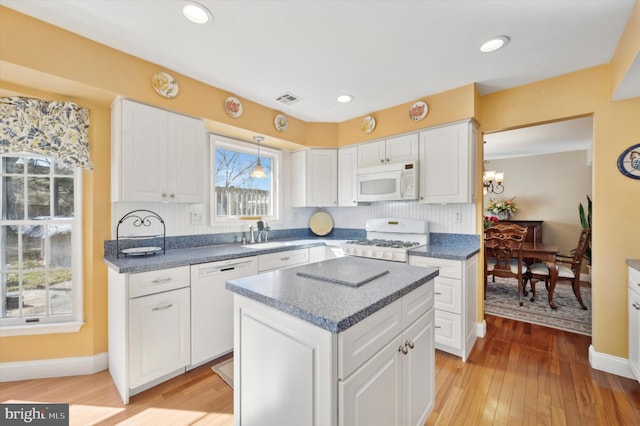 kitchen featuring a center island, white appliances, white cabinets, and visible vents