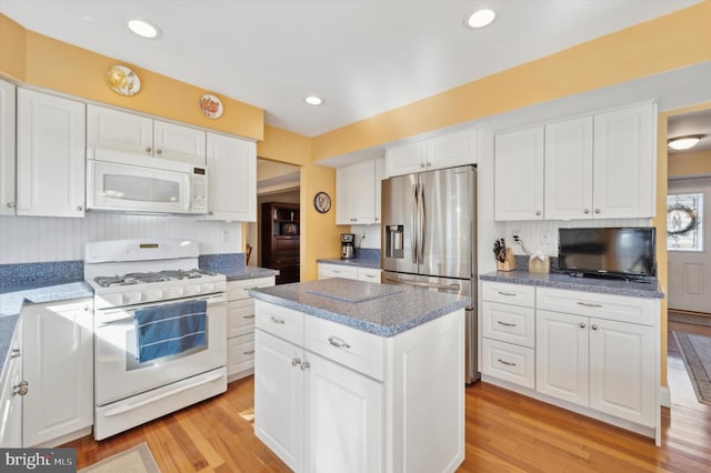 kitchen with white appliances, light wood-type flooring, white cabinets, and a center island