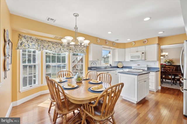 dining area featuring a chandelier, light wood-style flooring, recessed lighting, visible vents, and baseboards