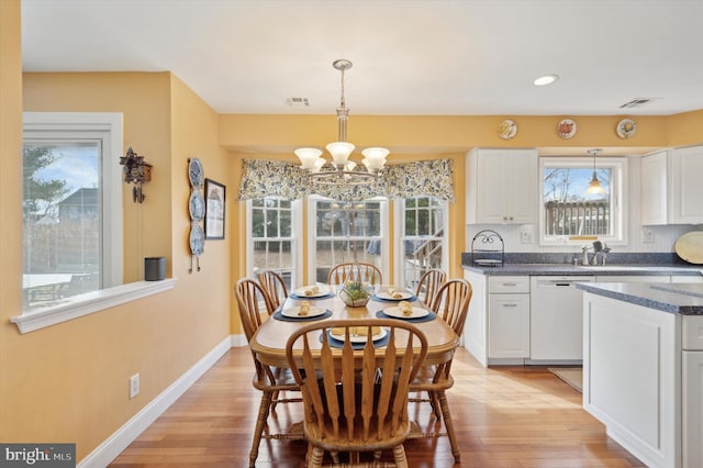 dining space with a notable chandelier, light wood finished floors, visible vents, and baseboards