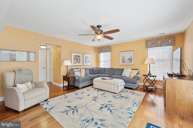 living room featuring a ceiling fan, plenty of natural light, baseboards, and wood finished floors