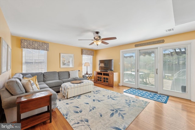 living room featuring a ceiling fan, a healthy amount of sunlight, visible vents, and wood finished floors