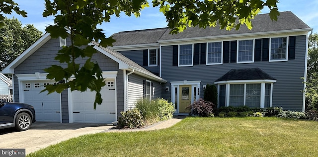 colonial-style house featuring a garage, concrete driveway, a front lawn, and roof with shingles