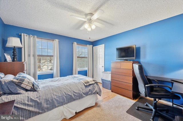 bedroom featuring ceiling fan, a textured ceiling, and light wood-style floors