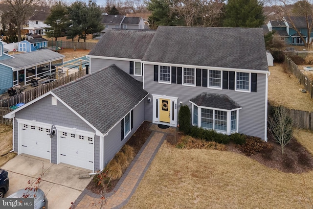 view of front of home with concrete driveway, a shingled roof, an attached garage, and a residential view