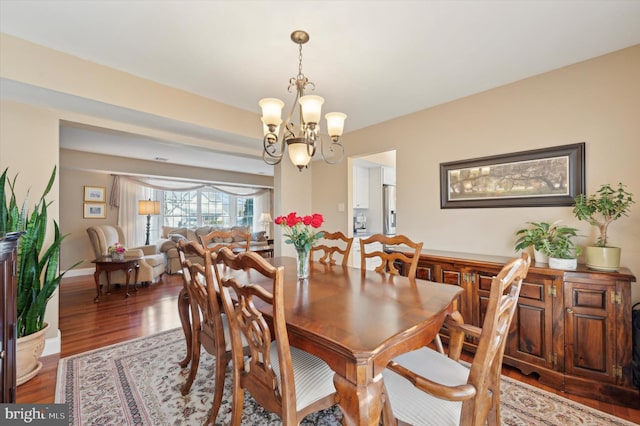 dining room featuring baseboards, wood finished floors, and a notable chandelier