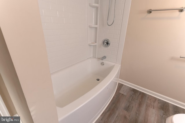 bathroom featuring toilet, tiled shower / bath combo, and hardwood / wood-style floors