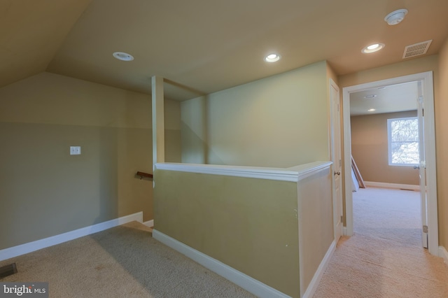 corridor featuring vaulted ceiling and light carpet