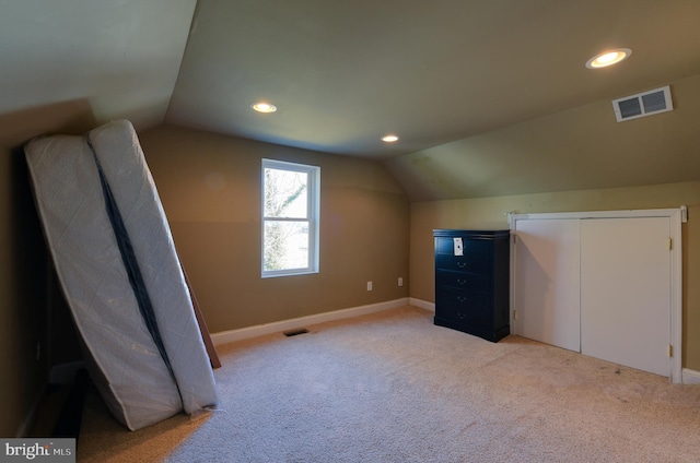 bonus room with lofted ceiling and light colored carpet