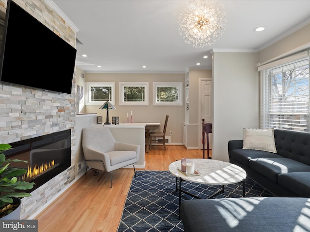 living room featuring a fireplace, a notable chandelier, light hardwood / wood-style flooring, and ornamental molding